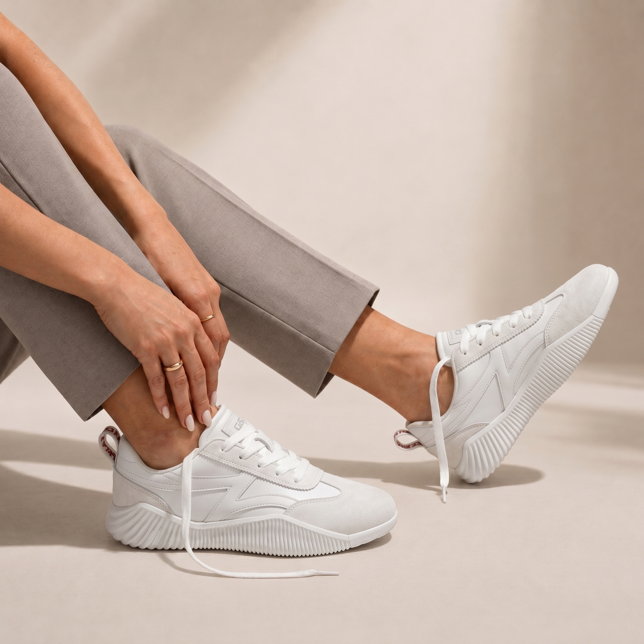Woman seated wearing DeFlorance Cloudea 2.0 sneakers in Triple White